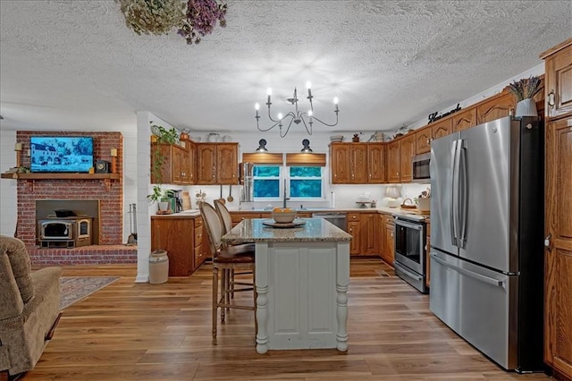 kitchen with light wood-type flooring, a breakfast bar area, appliances with stainless steel finishes, and a center island