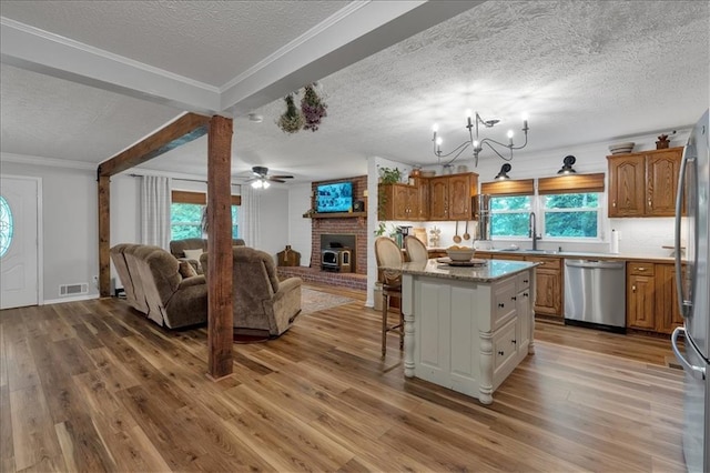 kitchen featuring a breakfast bar area, stainless steel appliances, plenty of natural light, a kitchen island, and sink