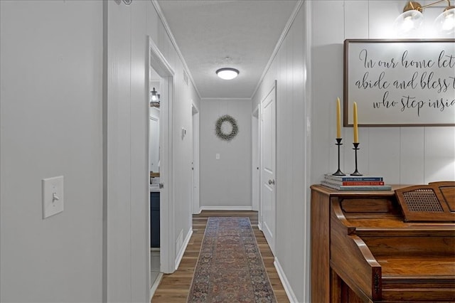 hallway featuring wood-type flooring, crown molding, and a textured ceiling