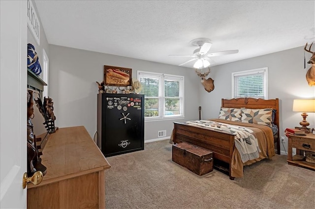 carpeted bedroom featuring ceiling fan and a textured ceiling