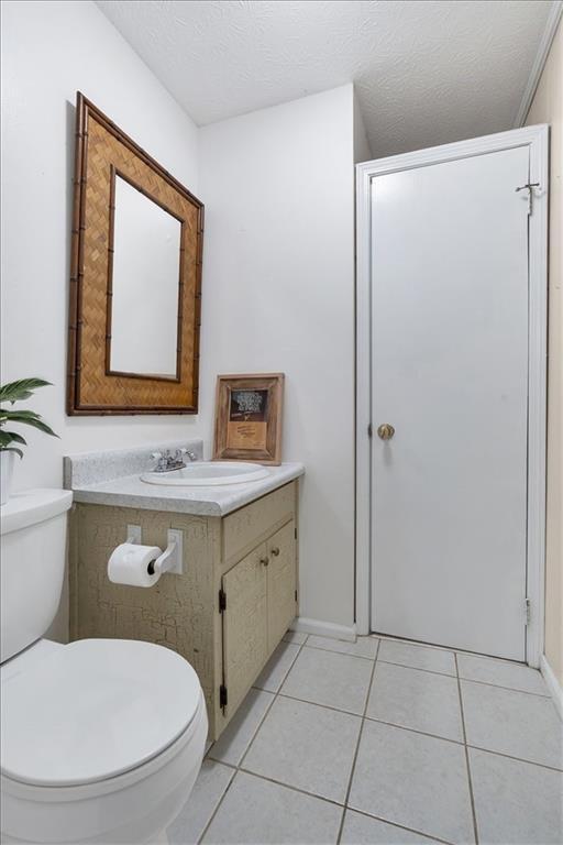 bathroom featuring toilet, vanity, tile patterned floors, and a textured ceiling