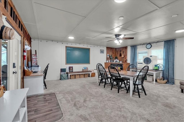 carpeted dining space with ceiling fan and wooden walls