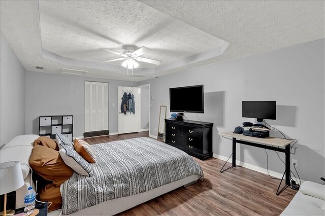 bedroom featuring ceiling fan, hardwood / wood-style flooring, a tray ceiling, and a closet