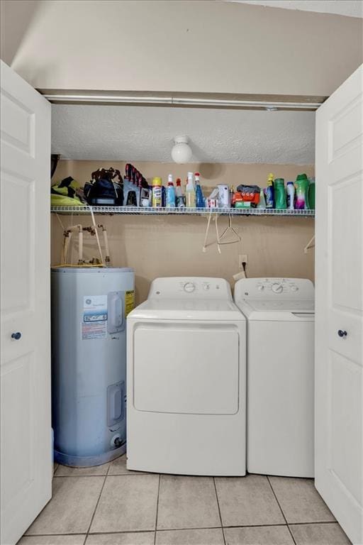 laundry area featuring washer and clothes dryer, water heater, and light tile patterned flooring