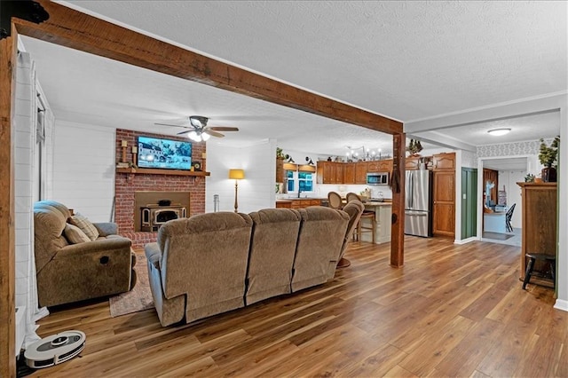 living room featuring a textured ceiling, ceiling fan, beam ceiling, and hardwood / wood-style floors