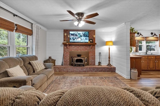 living room with light hardwood / wood-style floors, sink, crown molding, wooden walls, and a textured ceiling