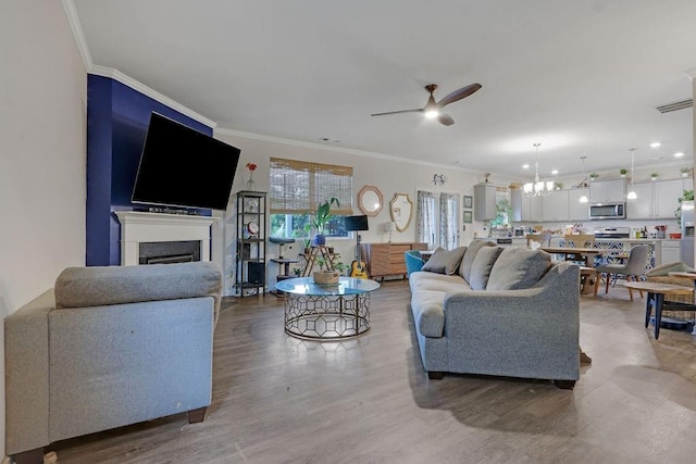 6721 Moondancer Ct, Flowery Branch, GA 30542 - living area featuring a ceiling fan, crown molding, light wood-type flooring, a fireplace, and a chandelier