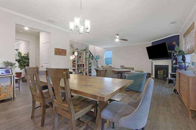 6721 Moondancer Ct, Flowery Branch, GA 30542 - dining room featuring wood finished floors, a fireplace, a ceiling fan, stairway, and ornamental molding