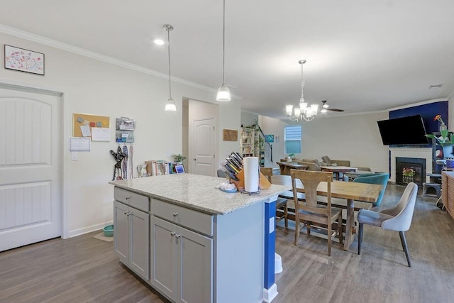 6721 Moondancer Ct, Flowery Branch, GA 30542 - kitchen with wood finished floors, crown molding, open floor plan, a kitchen island, and a fireplace