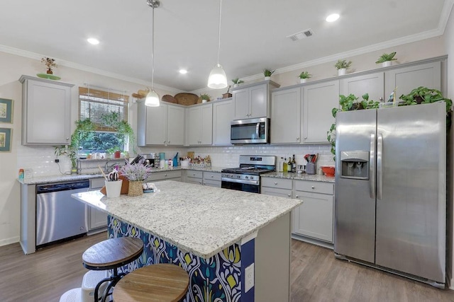 6721 Moondancer Ct, Flowery Branch, GA 30542 - kitchen with appliances with stainless steel finishes, wood finished floors, decorative backsplash, a breakfast bar, and crown molding
