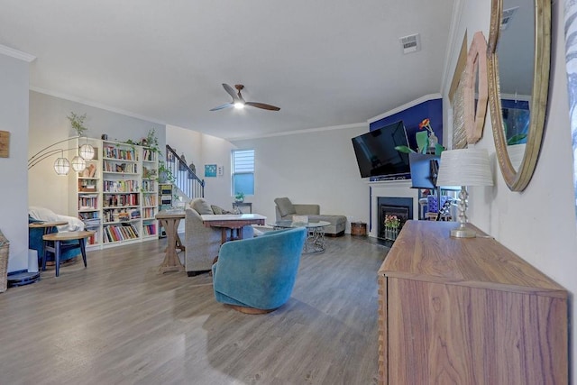 6721 Moondancer Ct, Flowery Branch, GA 30542 - living room with ceiling fan, wood finished floors, a fireplace, stairs, and ornamental molding