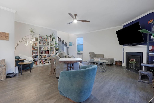 6721 Moondancer Ct, Flowery Branch, GA 30542 - living area with ceiling fan, wood finished floors, a fireplace with raised hearth, stairs, and crown molding