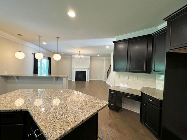 kitchen with light stone countertops, a kitchen breakfast bar, tasteful backsplash, and decorative light fixtures