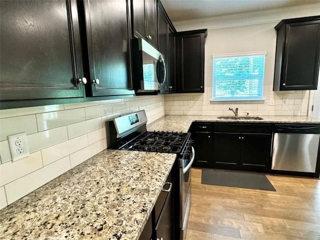 kitchen featuring sink, backsplash, appliances with stainless steel finishes, and light hardwood / wood-style flooring