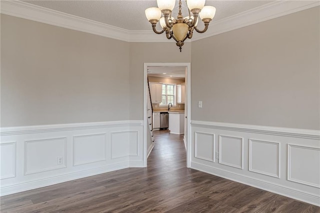 spare room featuring dark wood-type flooring, ornamental molding, and a notable chandelier