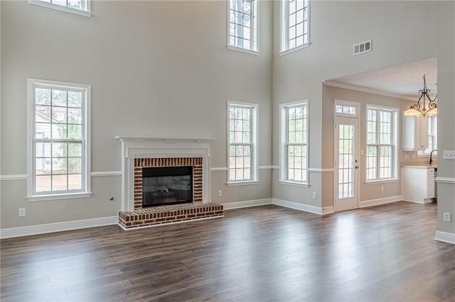 unfurnished living room featuring ornamental molding, plenty of natural light, dark hardwood / wood-style flooring, and a brick fireplace