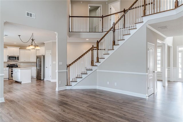 unfurnished living room featuring a high ceiling, ornamental molding, and light hardwood / wood-style flooring