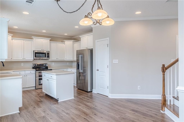 kitchen with sink, white cabinets, hanging light fixtures, a center island, and stainless steel appliances