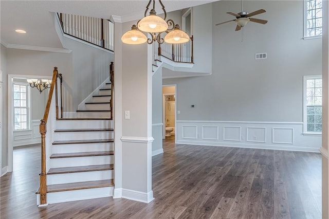 staircase with ornamental molding, wood-type flooring, and ceiling fan with notable chandelier