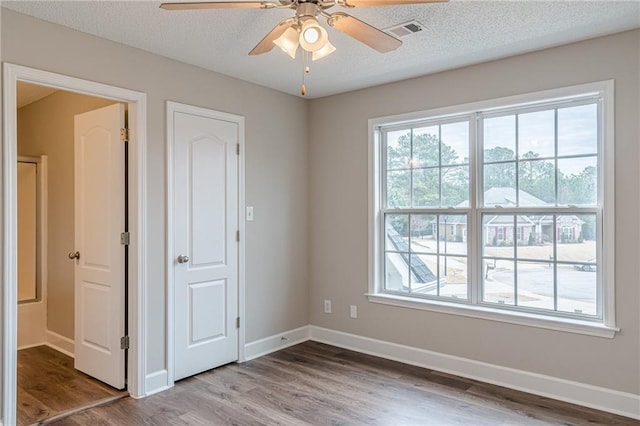 unfurnished room featuring ceiling fan, wood-type flooring, a textured ceiling, and a wealth of natural light