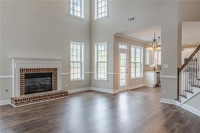 unfurnished living room with ornamental molding, dark hardwood / wood-style floors, sink, and a brick fireplace