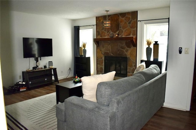 living room featuring a stone fireplace and dark hardwood / wood-style flooring