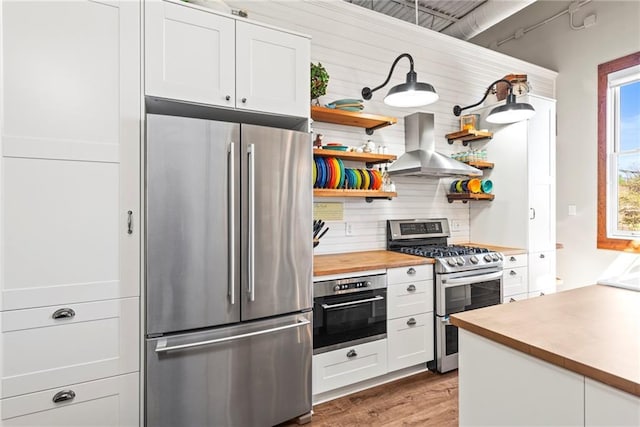 5097 Peachtree Rd Unit I, Atlanta, GA 30341 - kitchen featuring stainless steel appliances, island range hood, open shelves, butcher block counters, and wood finished floors