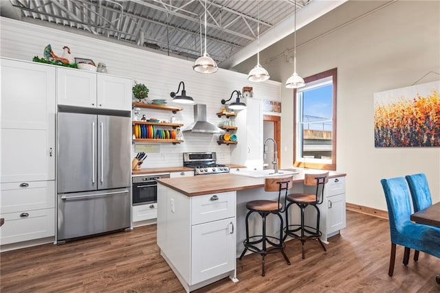 5097 Peachtree Rd Unit I, Atlanta, GA 30341 - kitchen featuring appliances with stainless steel finishes, wall chimney range hood, butcher block counters, open shelves, and dark wood finished floors