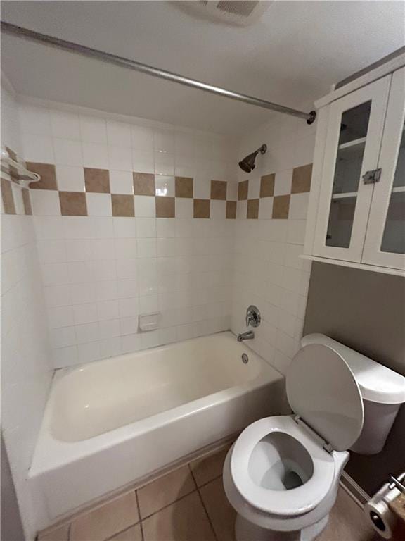 bathroom featuring tiled shower / bath, tile patterned floors, and toilet