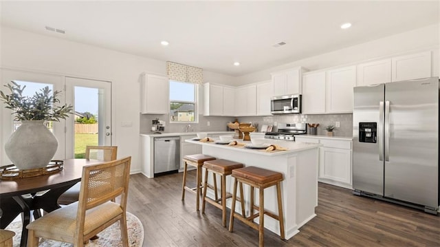 kitchen with appliances with stainless steel finishes, white cabinetry, a center island, and dark wood-type flooring