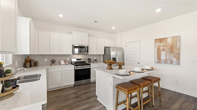 kitchen featuring a kitchen island, sink, white cabinets, appliances with stainless steel finishes, and dark hardwood / wood-style flooring