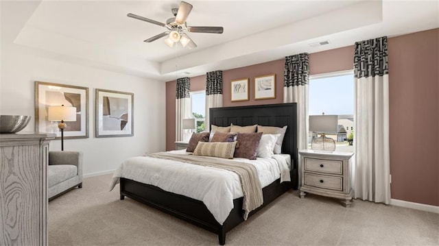 carpeted bedroom with multiple windows and a tray ceiling