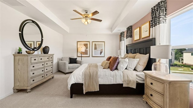 carpeted bedroom featuring ceiling fan, a raised ceiling, and multiple windows