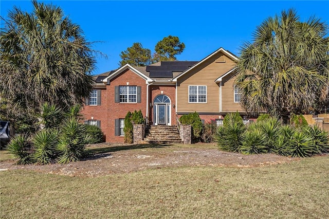 view of front of home with a front yard and solar panels