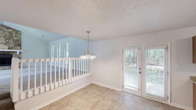 1169 Oaks Pl, Stone Mountain, GA 30083 - unfurnished dining area with healthy amount of natural light, a chandelier, a fireplace, vaulted ceiling, and a textured ceiling