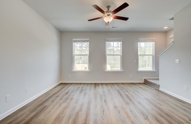 empty room with a ceiling fan, baseboards, visible vents, and wood finished floors