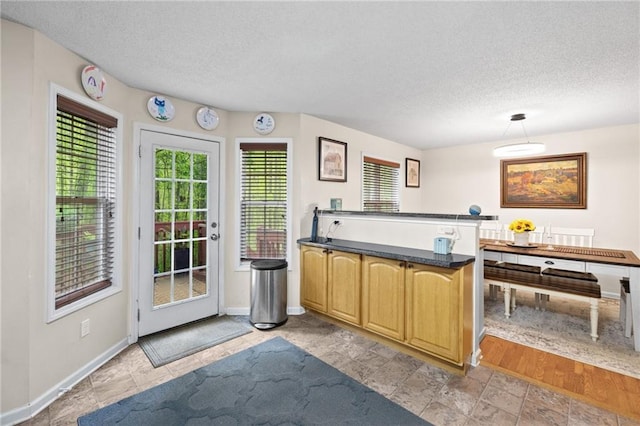 69 Due W Pass, Dallas, GA 30157 - kitchen with a peninsula, a textured ceiling, dark countertops, baseboards, and pendant lighting