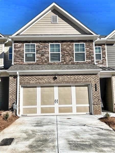 view of front facade with brick siding, an attached garage, a shingled roof, and driveway