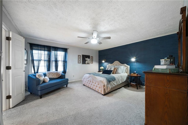 carpeted bedroom featuring a textured ceiling, an accent wall, a ceiling fan, and baseboards