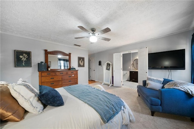 carpeted bedroom featuring visible vents, ornamental molding, a ceiling fan, a textured ceiling, and ensuite bath