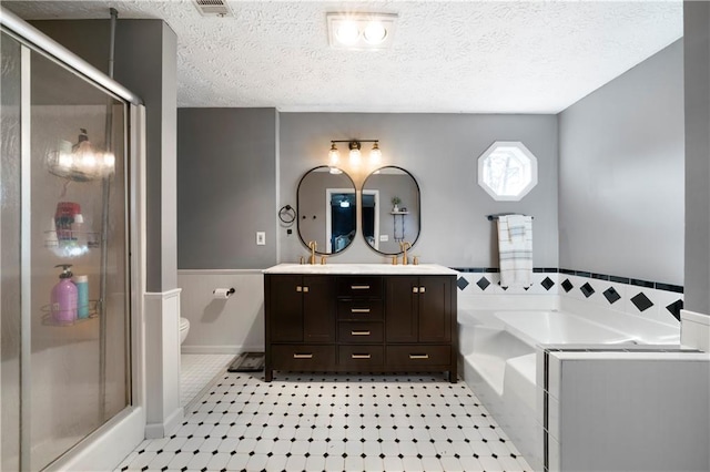 full bathroom with a sink, a textured ceiling, a shower stall, and toilet