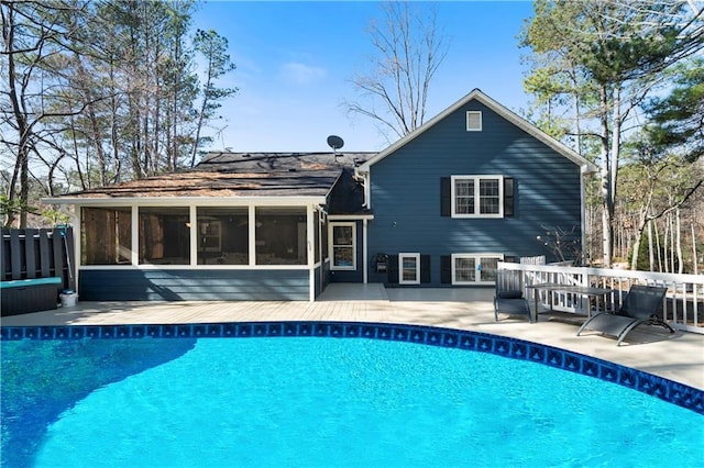 rear view of property featuring a sunroom and an outdoor pool