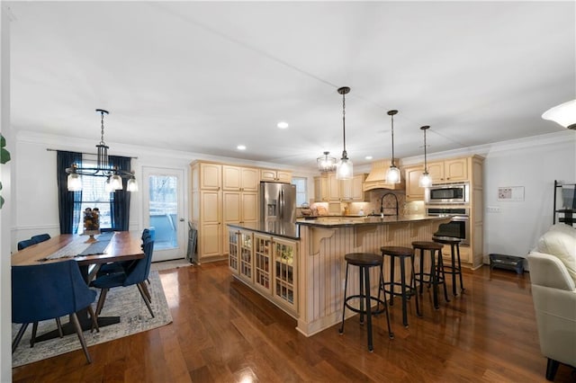 kitchen featuring stainless steel appliances, dark wood-style flooring, ornamental molding, light brown cabinetry, and dark countertops