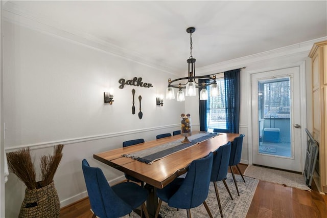 dining area featuring light wood-style floors, baseboards, ornamental molding, and a chandelier