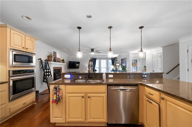 kitchen with open floor plan, stainless steel appliances, crown molding, a brick fireplace, and a sink