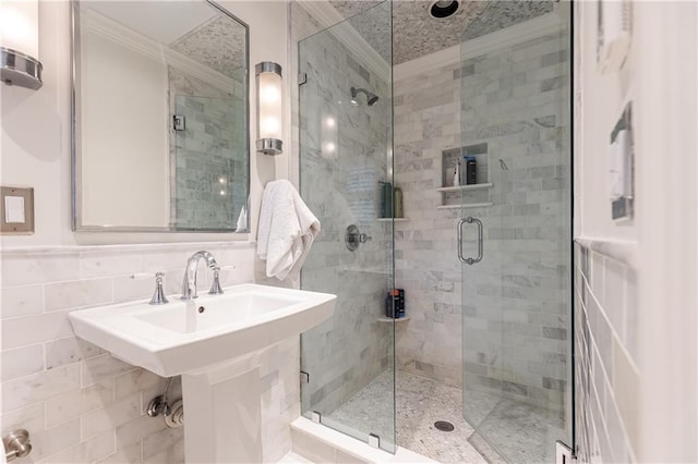 bathroom with a shower with door, tile walls, and sink