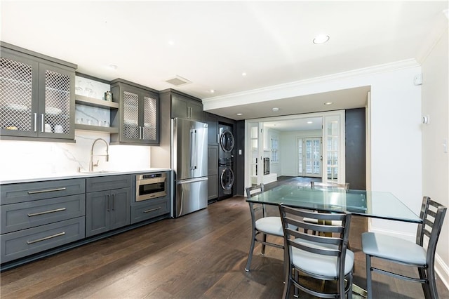 kitchen featuring gray cabinetry, sink, stacked washer / dryer, and appliances with stainless steel finishes