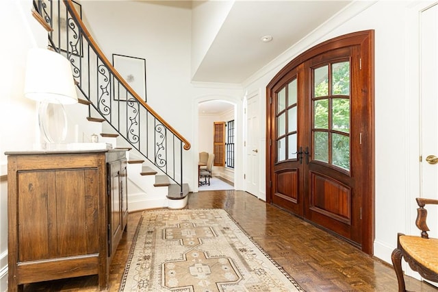 entrance foyer with french doors, dark parquet floors, and ornamental molding