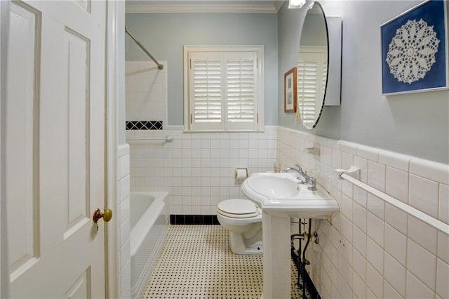 full bathroom featuring ornamental molding, wainscoting, shower / bathtub combination, toilet, and tile walls