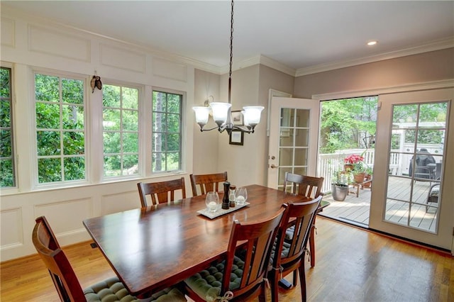 dining room featuring light wood-style floors, a notable chandelier, a healthy amount of sunlight, and a decorative wall